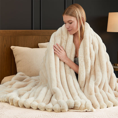 Woman wrapped in a plush white blanket on a bed. #color_Beige