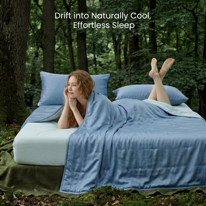 Person lying on a mattress outdoors with blue bedding, surrounded by trees.#color_Dark Blue