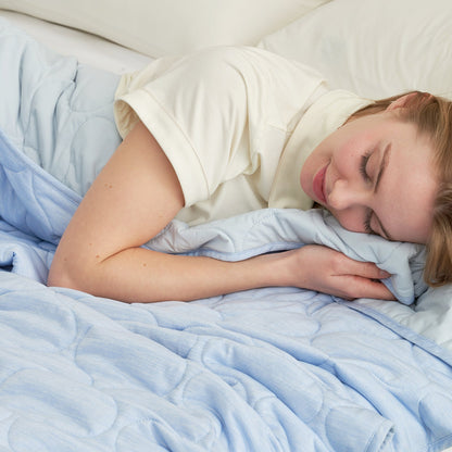 Woman sleeping peacefully under a cool blue cooling blanket, showcasing the cozy comfort of the dual-sided design #color_Cool Blue