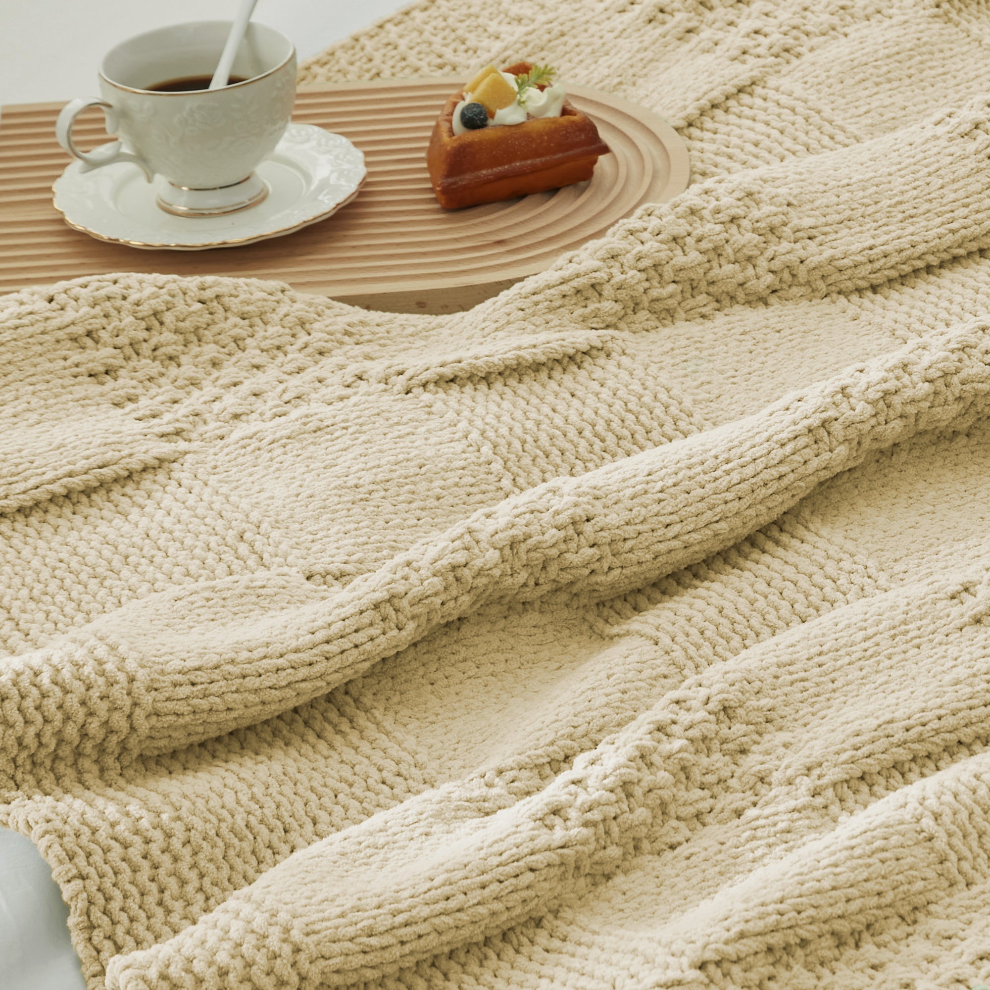 Close-up of Checkered Chenille Knit Throw Blanket in Beige showcasing textured chenille knit pattern with a cozy tea and dessert setting. #color_Beige