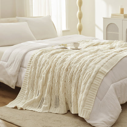 Chenille Cable Knit Throw Blanket in Ivory styled on a bed in a bright bedroom, adding a clean and cozy layered look. #color_Ivory
