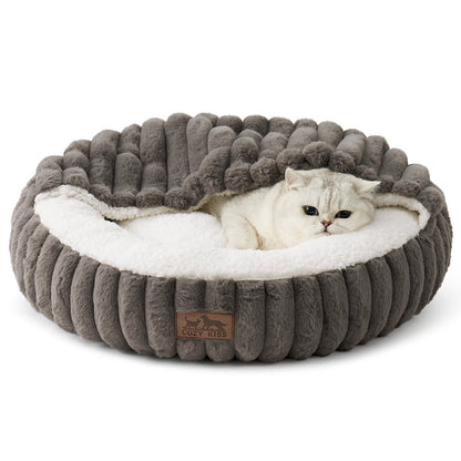 Cat lying on a fluffy grey faux fur pet bed with hooded blanket in a cozy room with wooden furniture and a rug.#color_Grey