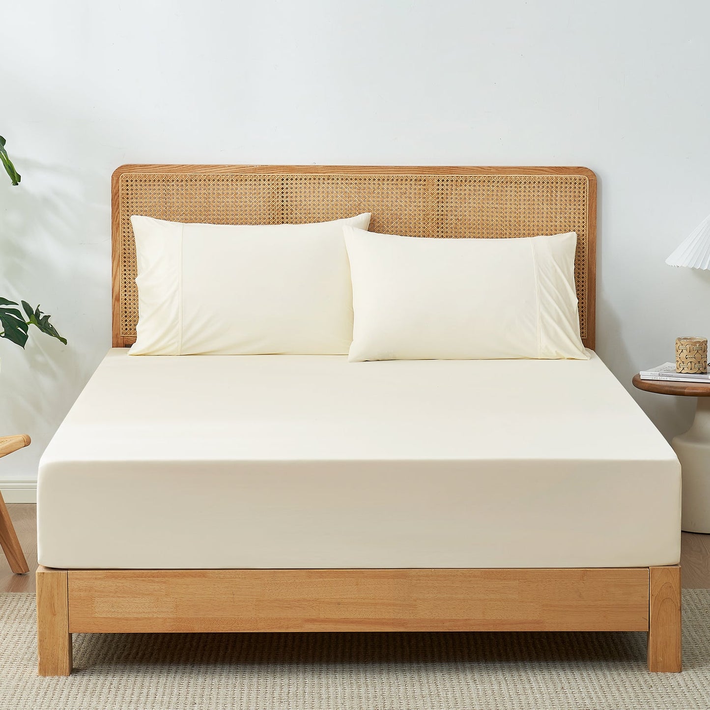 Cream-colored cooling fitted sheet set with pillowcases on a bed with wooden headboard. #Color_Cream White