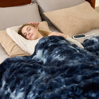 Woman sleeping under a tie-dye blue heated electric blanket with a remote control on a bed.  #color_Tie-dye Blue