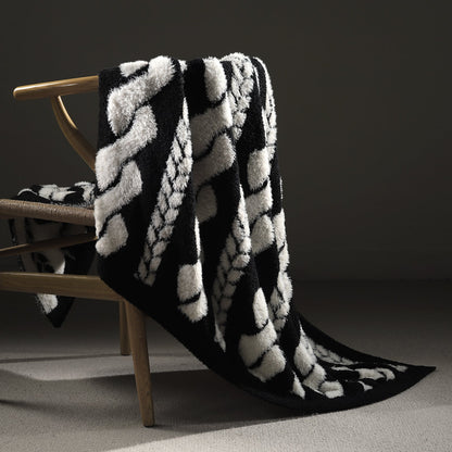 Faux Mink Cable Knit Throw Blanket in Black draped over a chair, showcasing plush texture and elegant cable knit design. #color_Black