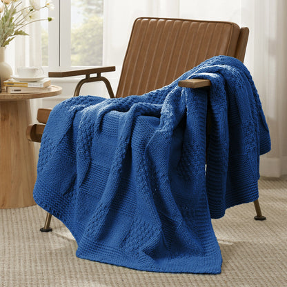 Checkered Chenille Knit Throw Blanket in Blue draped over a lounge chair, showcasing soft chenille knit texture and cozy checkered design. #color_Blue