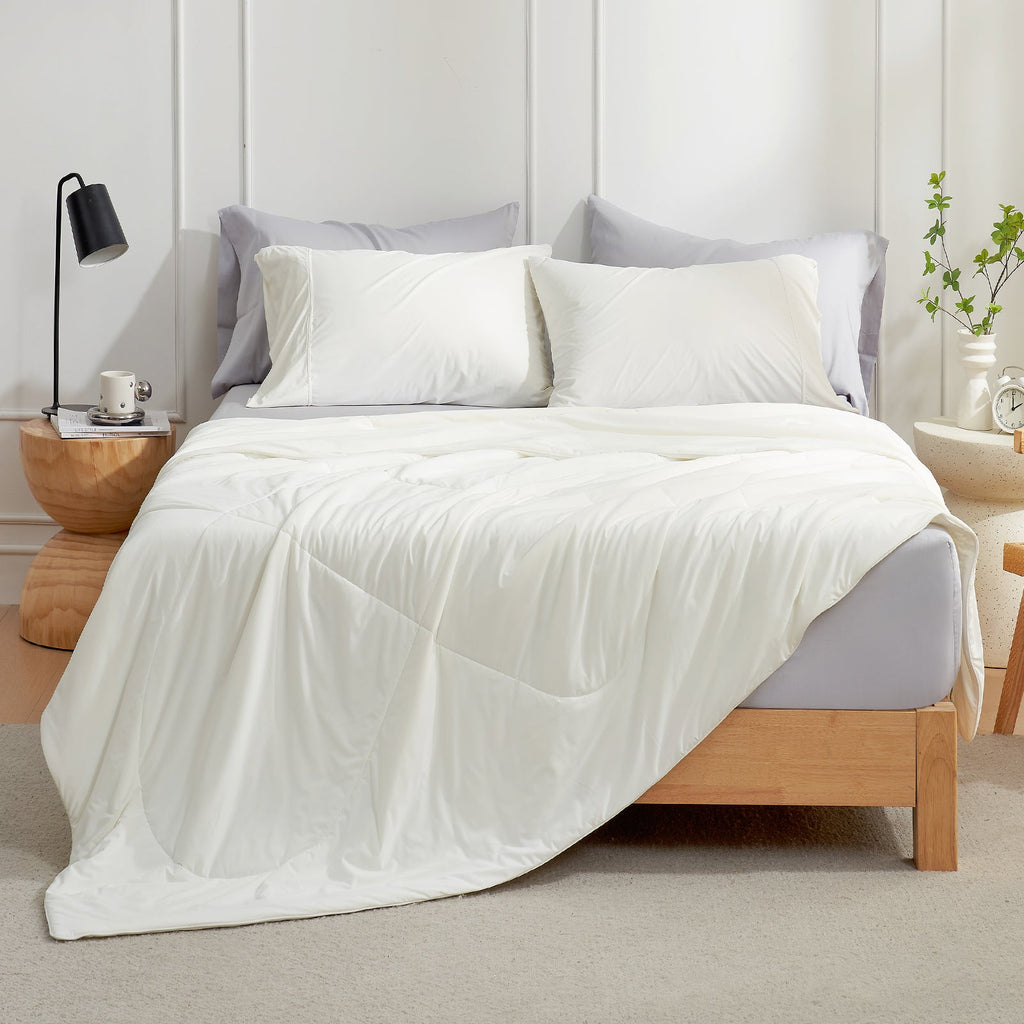 White cooling comforter and pillows on a bed, offering soft, breathable comfort for a cozy sleep experience. #Color_Off White