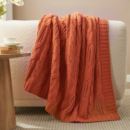 Chenille Cable Knit Throw Blanket in Burnt Orange draped over a sofa, creating a warm atmosphere. #color_Burnt Orange
