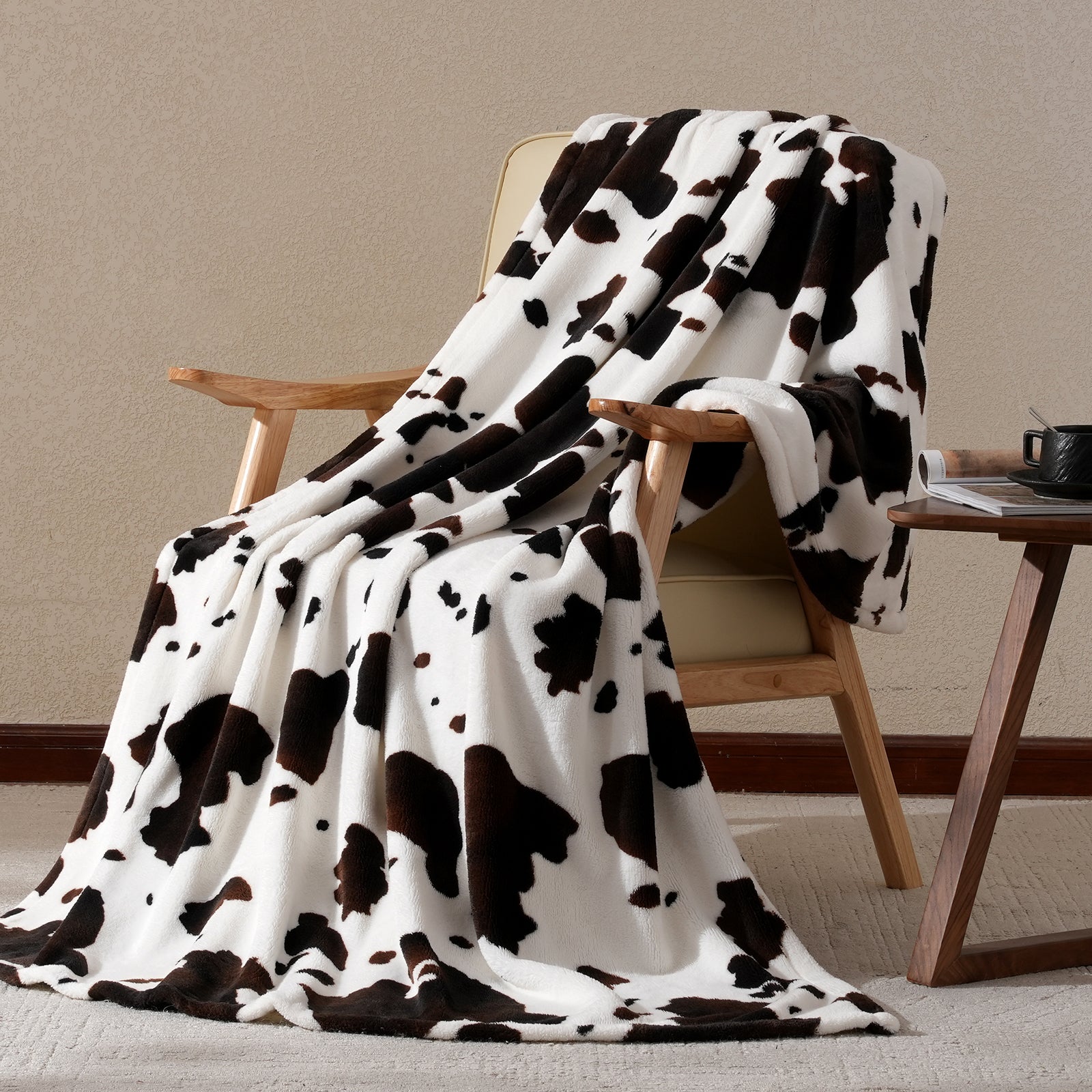 Cow print milkyplush throw blanket in Black Brown draped over a chair, creating a cozy and stylish corner #color_Black Brown