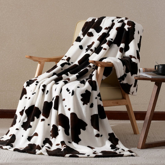 Cow print milkyplush throw blanket in Black Brown draped over a chair, creating a cozy and stylish corner #color_Black Brown