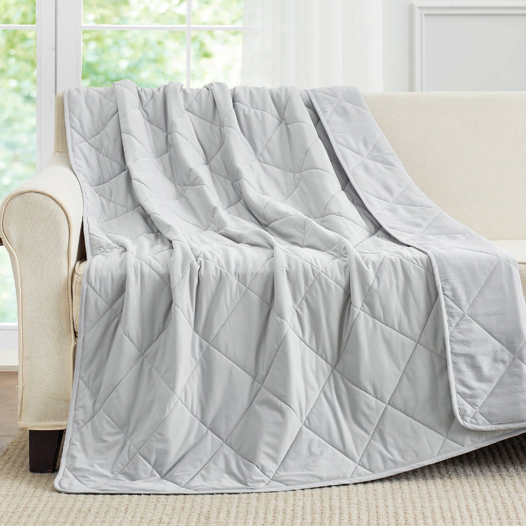 Cool grey cooling blanket draped over a beige sofa. #Color_Cool Grey