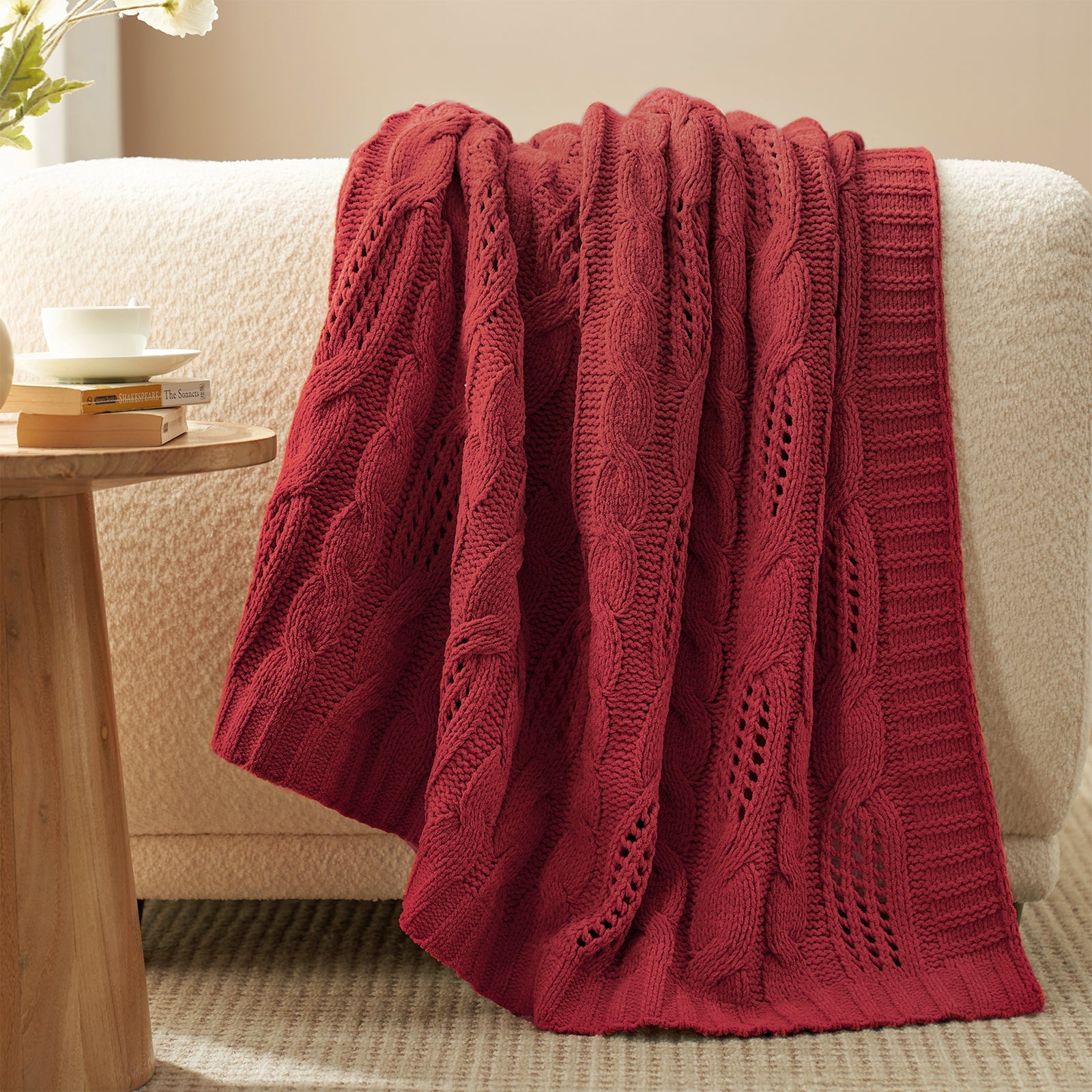 Chenille Cable Knit Throw Blanket in Red draped over a sofa, creating a warm atmosphere. #color_Red