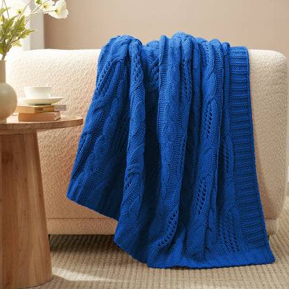 Chenille Cable Knit Throw Blanket in Blue draped over a sofa, creating a warm atmosphere. #color_Blue