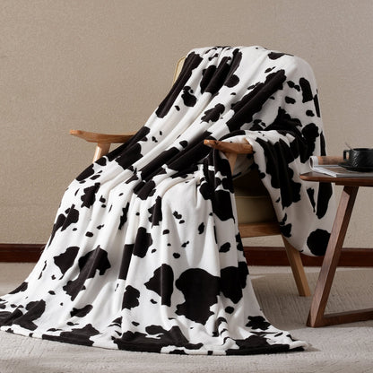 Cow print milkyplush throw blanket in Black White draped over a chair, creating a cozy and stylish corner #color_Black White