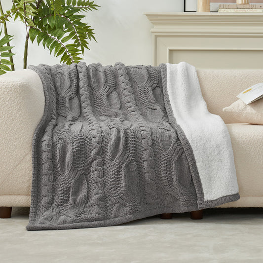 Reversible Cable Chenille Sherpa Knit Throw Blanket in Grey draped over a sofa, showcasing its textured cable knit design and soft sherpa lining. #color_Grey
