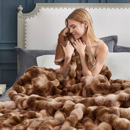 Woman wrapped in a fluffy tie-dye brown faux fur blanket on a bed. #color_Tie-dye Brown