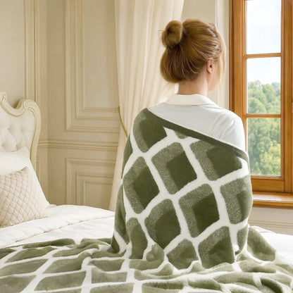 Woman wrapped in Diamond Feather Yarn Throw Blanket in Green sitting by the window, enjoying a cozy and relaxing moment at home. #color_Green
