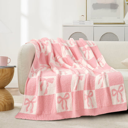 Reversible Checkered Bow Feather Yarn Throw Blanket in Pink draped over a sofa, showcasing soft feather yarn texture and bow checkered pattern design. #color_Pink