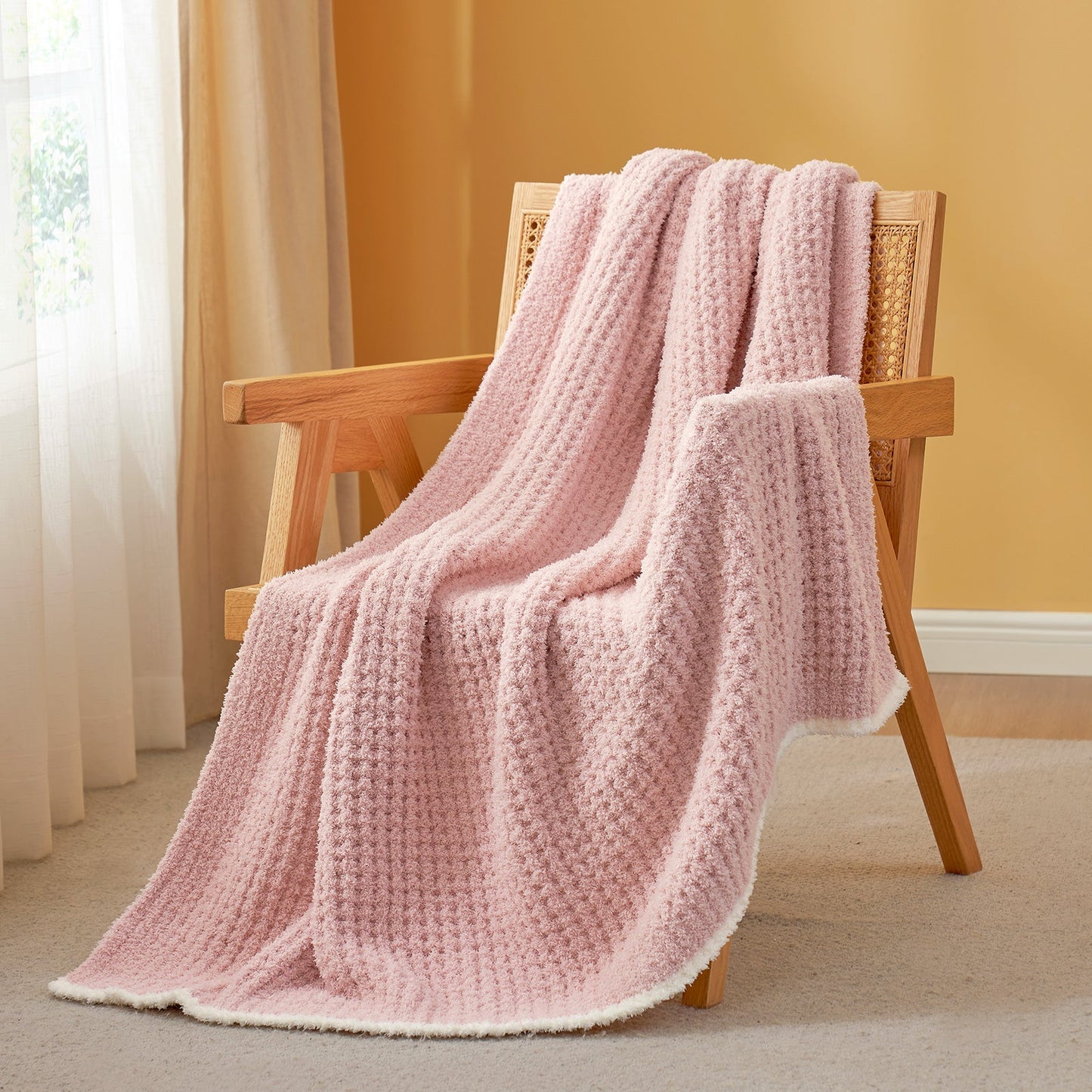 Soft Waffle Feather Yarn Throw Blanket in Pink draped over an armchair, creating a warm atmosphere. #color_Pink