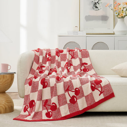 Reversible Checkered With Red Cherry Throw Blanket in Red Cherry draped over a sofa, showcasing cozy texture and playful cherry pattern design. #color_Red Cherry