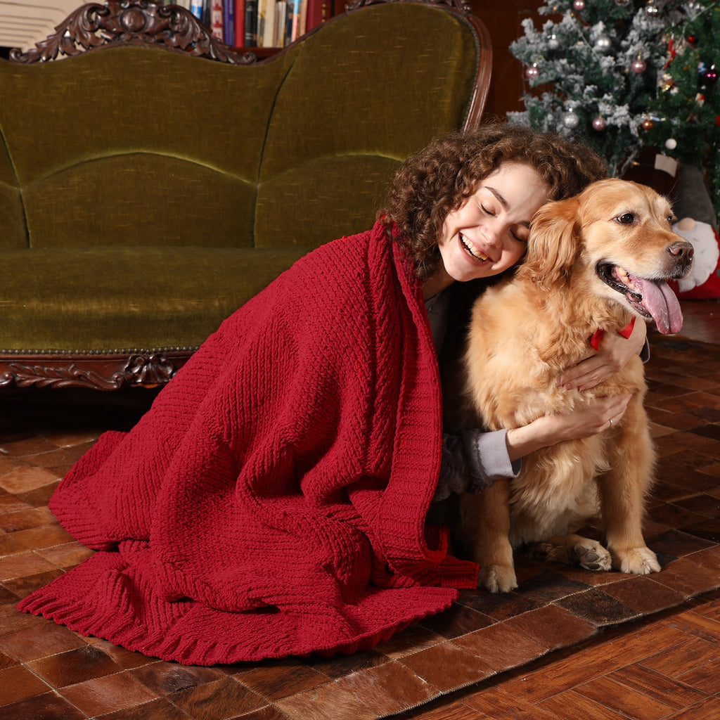 Woman hugging a golden dog with a red blanket in a cozy living room. #color_Red