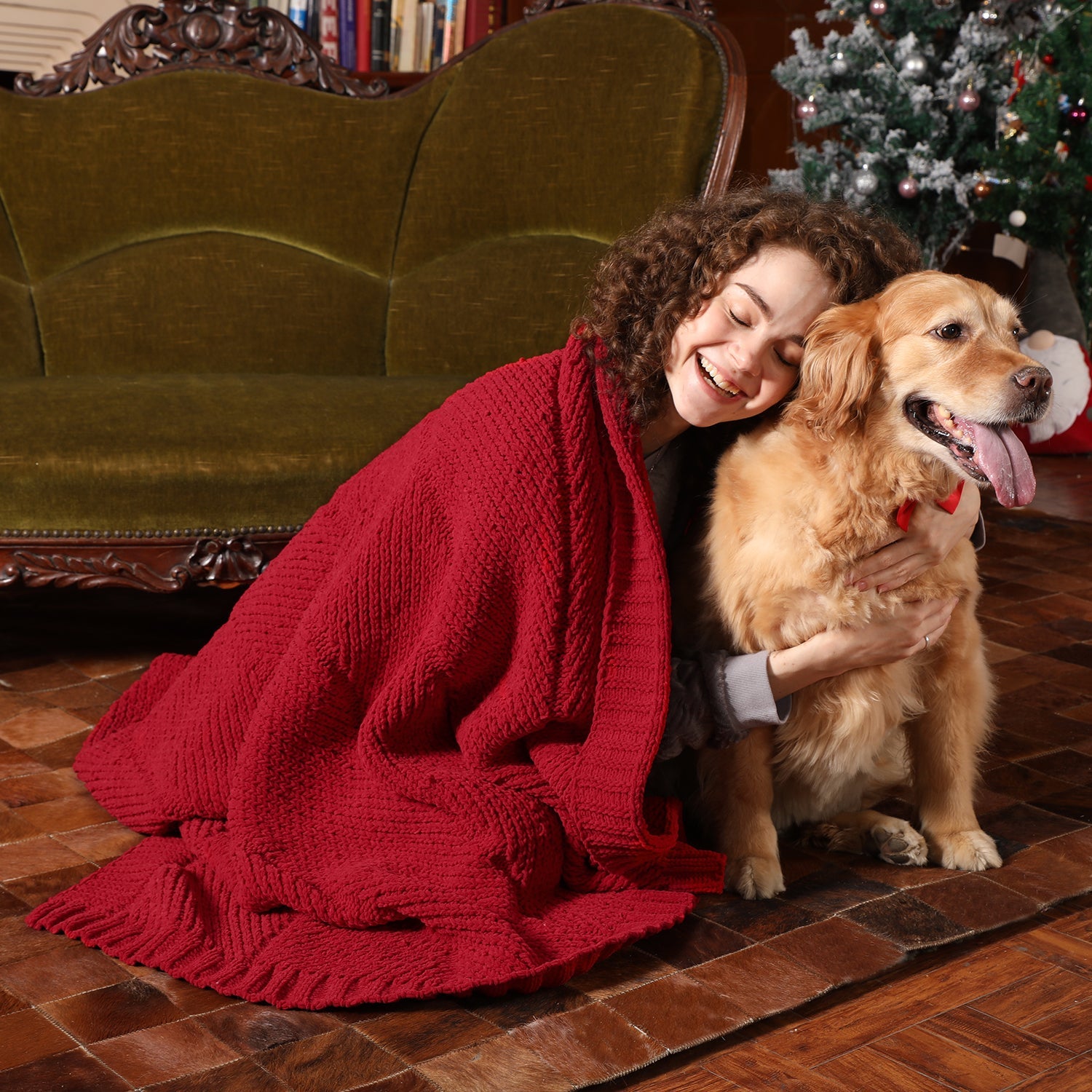 Woman hugging a golden dog with a red blanket in a cozy living room. #color_Red