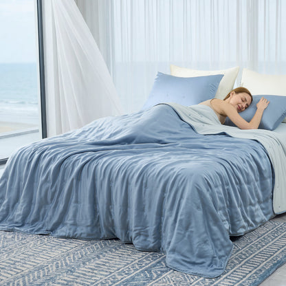 Woman sleeping peacefully under blue silky smooth Tencel™ lyocell cooling comforter. #Color_Dark Blue