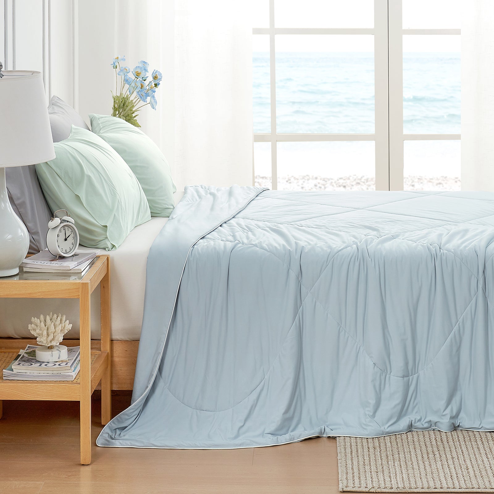 Cozy Bliss cooling blanket in bedroom setting, ocean view #Color_Cool Blue