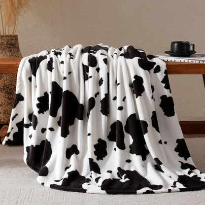 Cow print milkyplush throw blanket in Black White draped over a desk #color_Black White