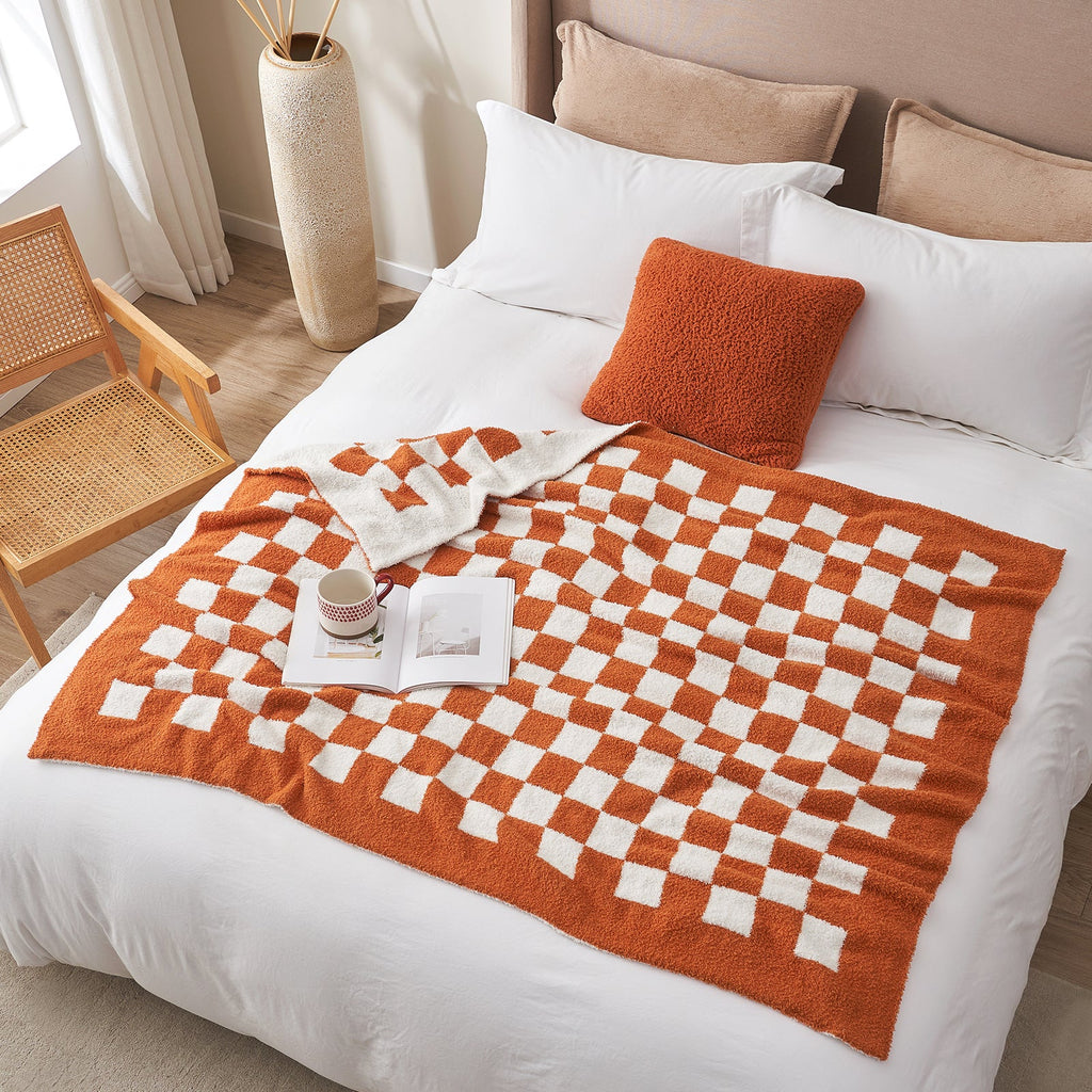 Checkered Feather Yarn Knit Throw Blanket in Burnt Orange styled on a bed in a bright bedroom. #Color_Burnt Orange