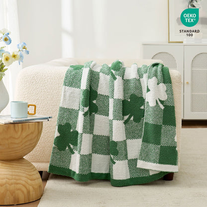 Green and white checkered blanket with shamrock design draped over a chair in a room. #color_Lucky Clover