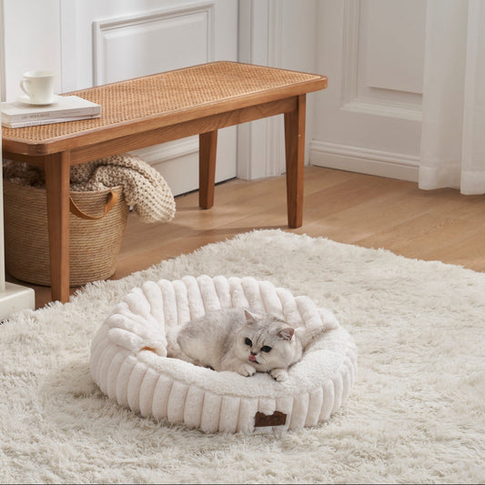 Cat lying on a fluffy white faux fur pet bed with hooded blanket in a cozy room with wooden furniture and a rug.#color_Cream Wite