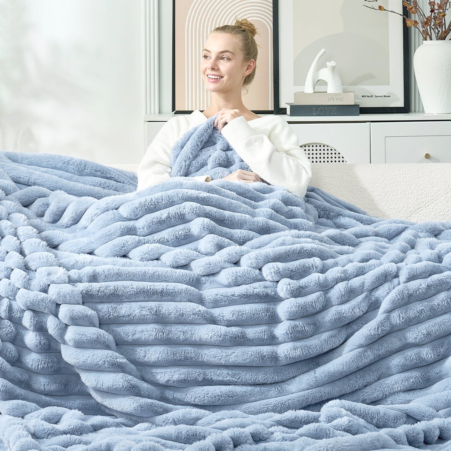 Woman wrapped in a large light blue striped faux fur throw blanket in a cozy living room. #color_Misty Blue