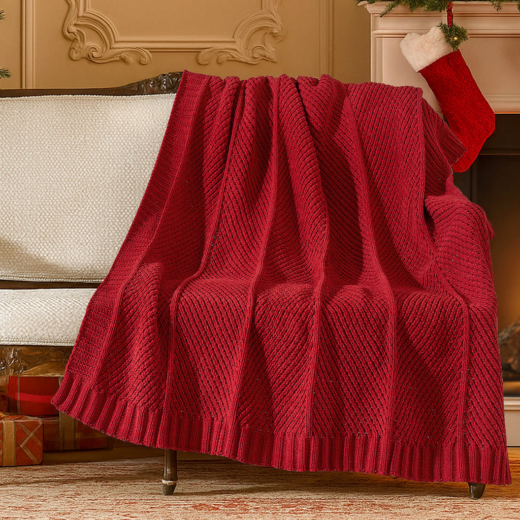 Red knitted blanket draped over a sofa in a festive living room with Christmas stockings and presents. #color_Red