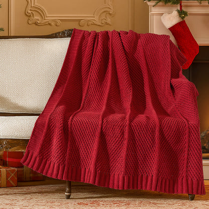 Red knitted blanket draped over a sofa in a festive living room with Christmas stockings and presents. #color_Red