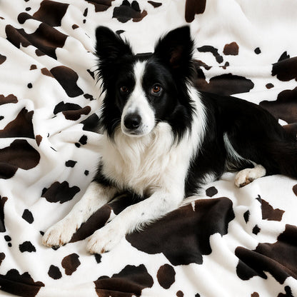 Dog resting on a cow print milkyplush throw blanket in Black Brown, creating a relaxed and cozy setting #color_Black Brown