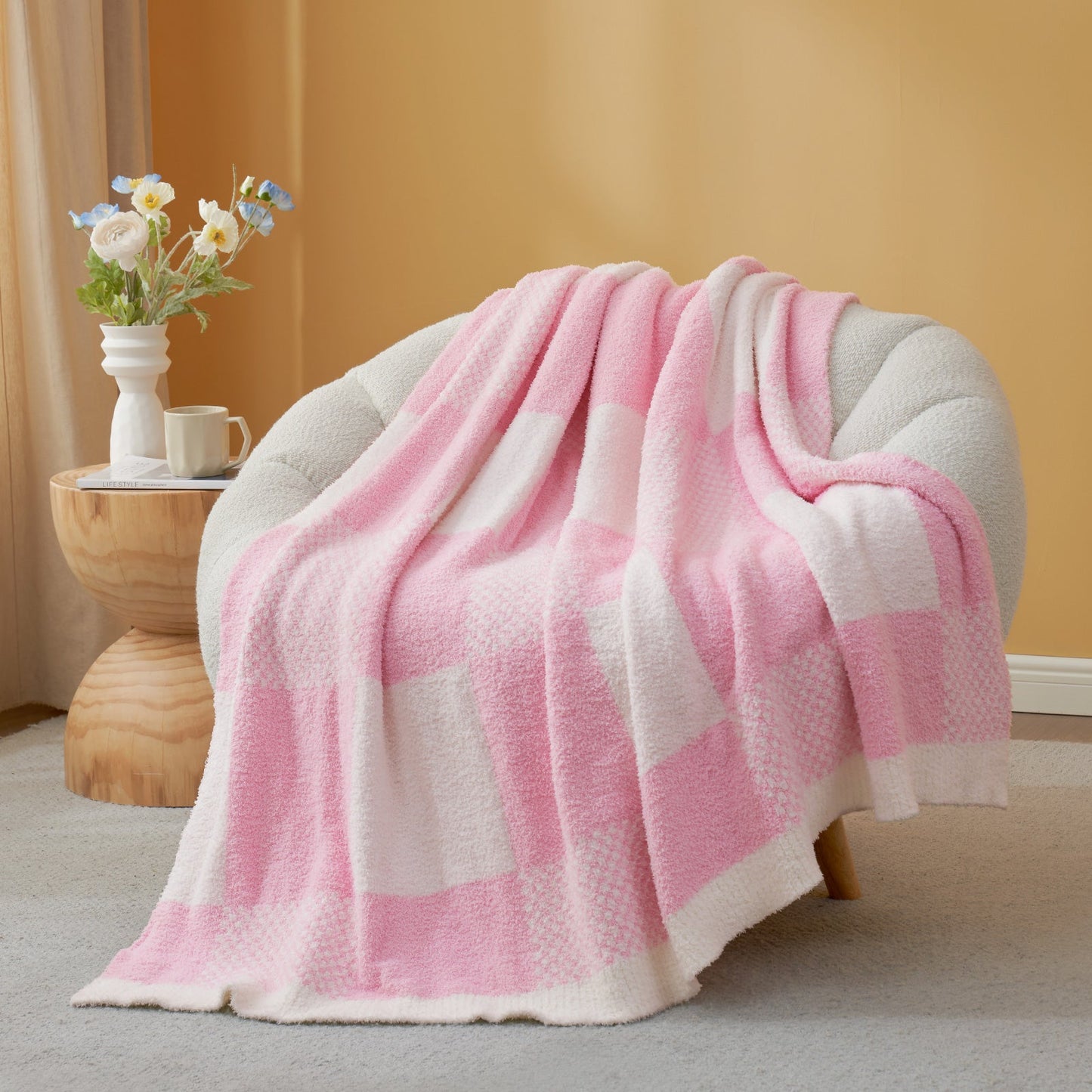 Pink and white checkered blanket draped over a chair in a cozy room.#color_Pink