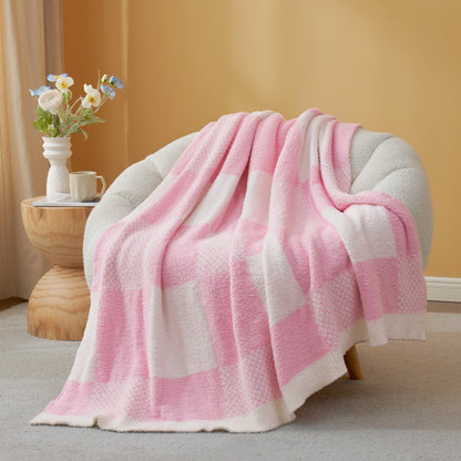 Pink and white checkered blanket draped over a chair in a cozy room.#color_Pink