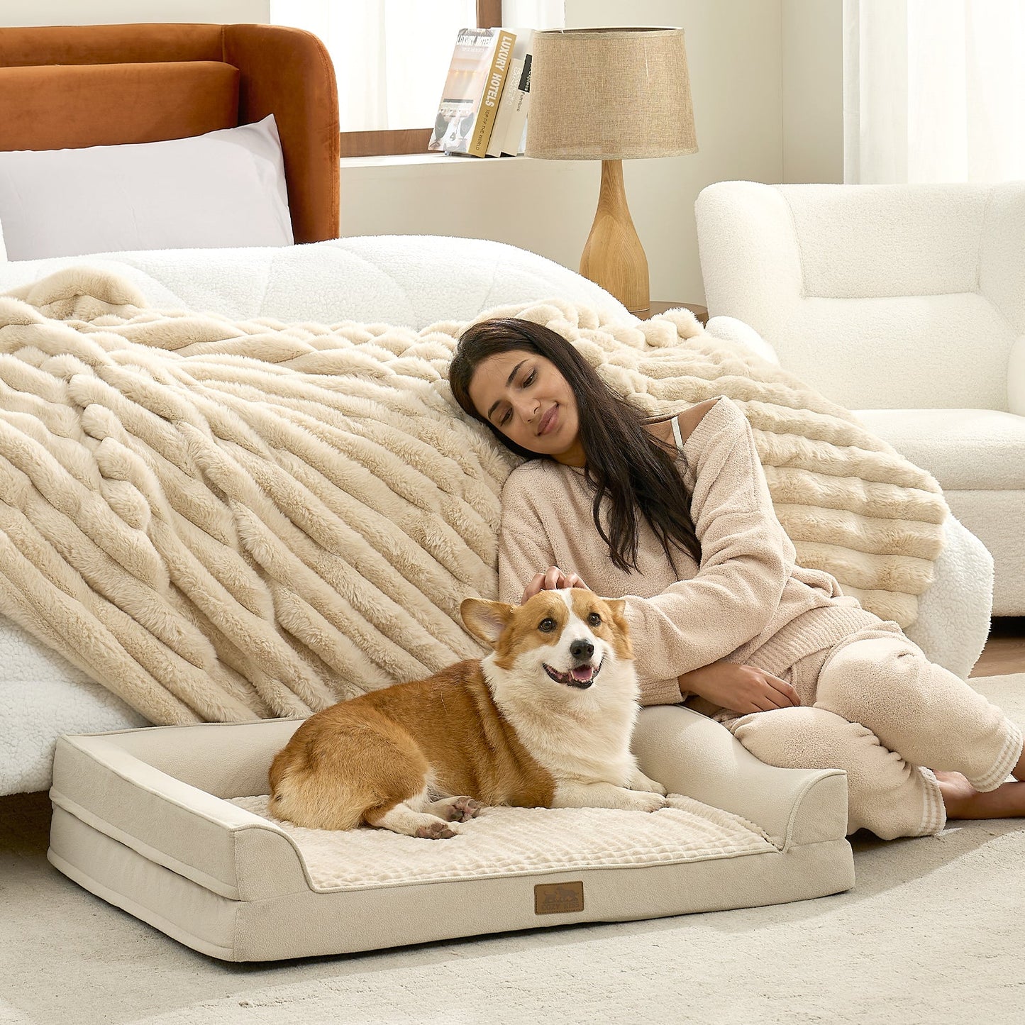 Dog lying on a Cozy Bliss Beige pet bed in a living room with a woman sitting beside it.#Beige