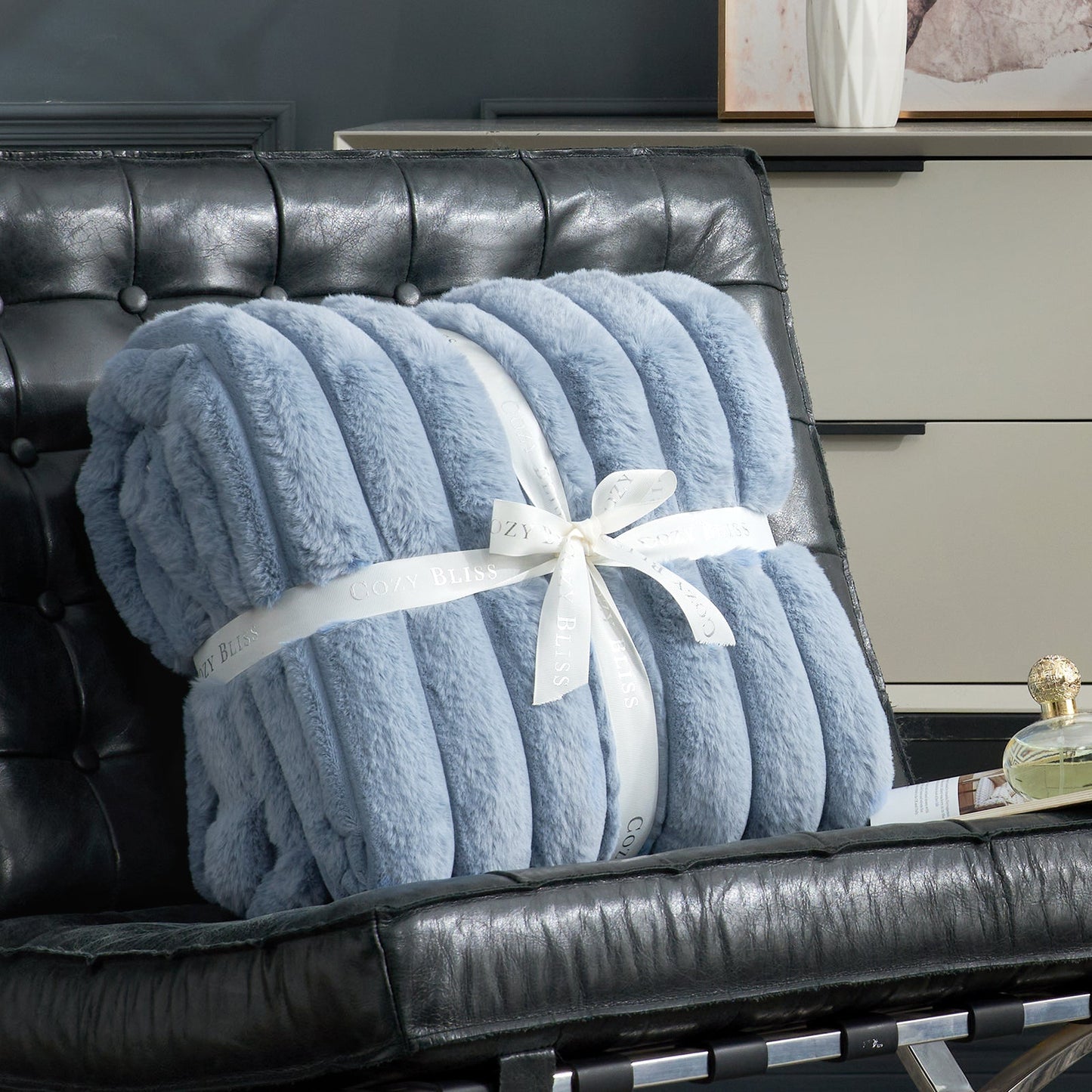 Fluffy blue striped faux fur throw blanket with a bow on a sofa. #color_Misty Blue