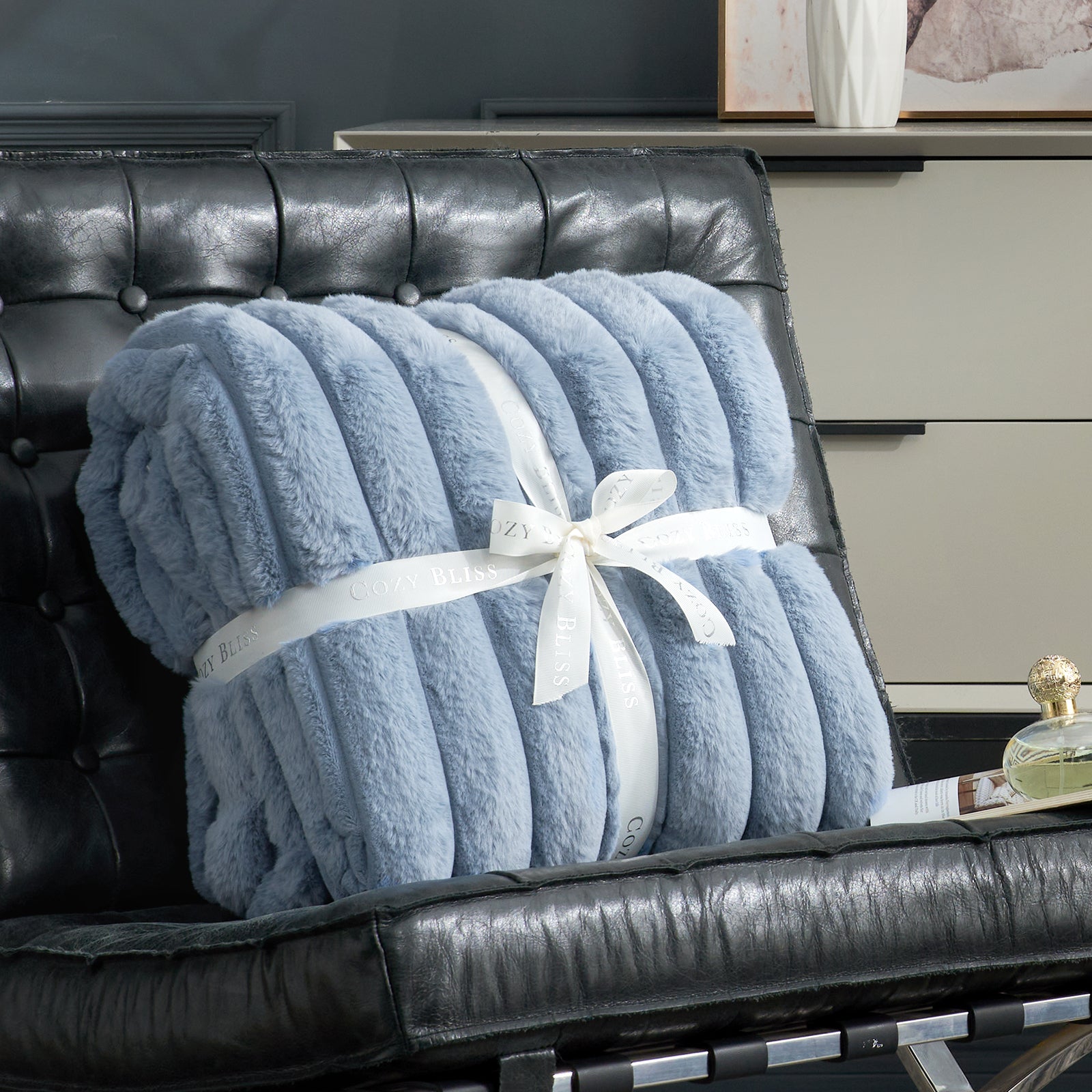 Fluffy blue striped faux fur throw blanket with a bow on a sofa. #color_Misty Blue
