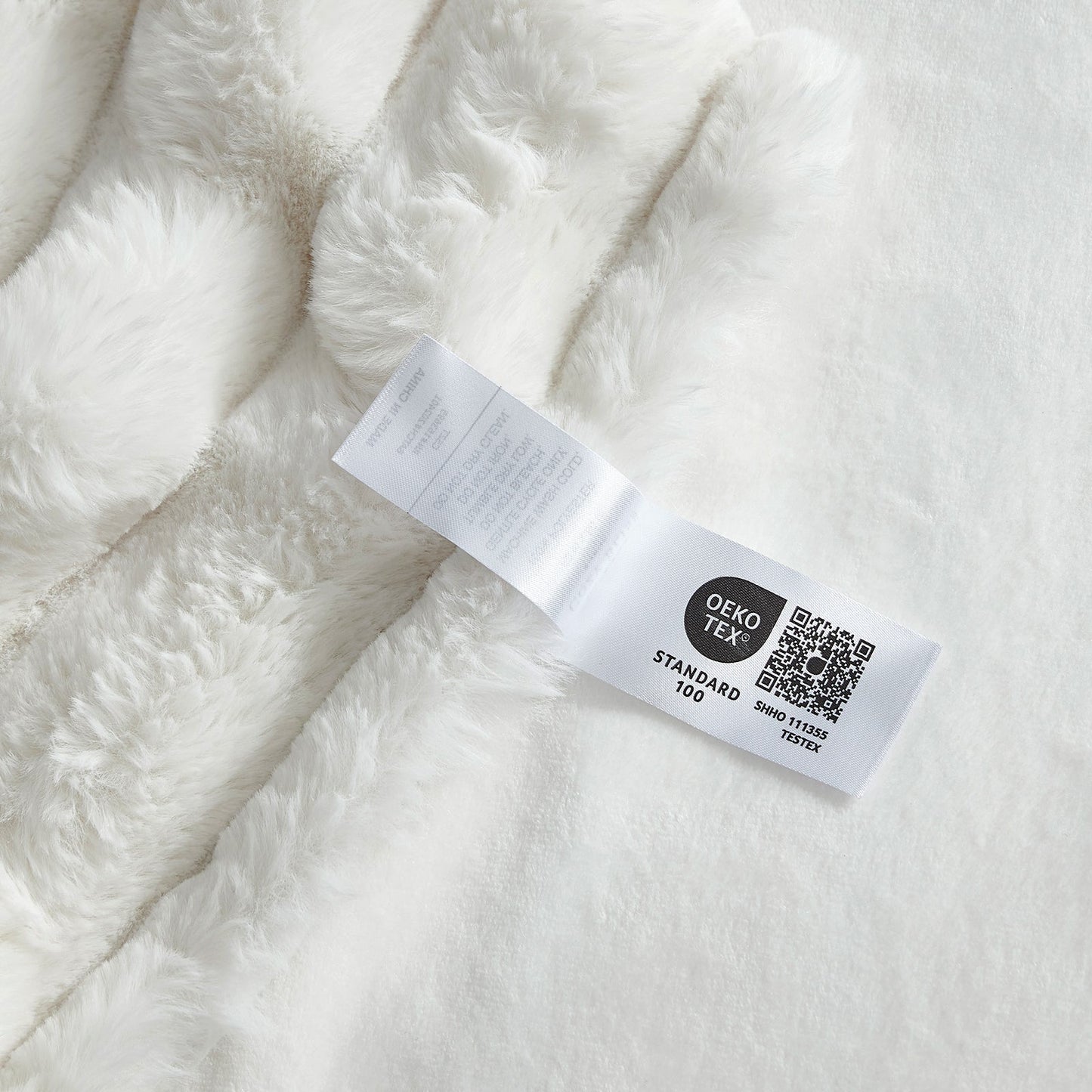 Close-up of OEKO-TEX certified label of  Cozy Bliss faux fur blanket  #color_Cream White