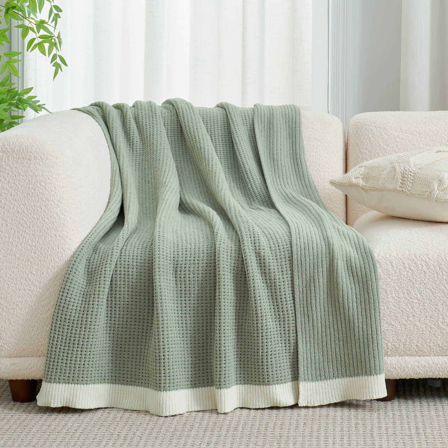 Chenille Waffle Knit Throw Blanket in Sage Green draped over a sofa, showcasing its soft tone and cozy texture. #color_Sage Green