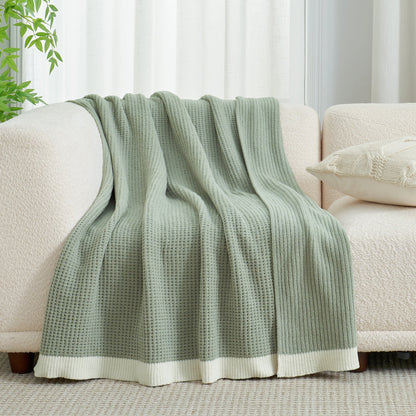 Chenille Waffle Knit Throw Blanket in Sage Green draped over a sofa, showcasing its soft tone and cozy texture. #color_Sage Green