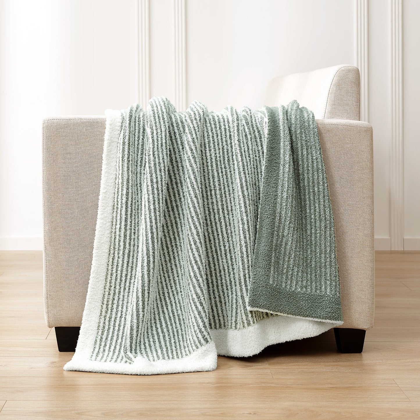 Soft Ribbed Feather Yarn Throw Blanket in Sage Green & White draped over the back of a sofa, highlighting soft ribbed texture and cozy fabric feel. #color_Sage Green & White