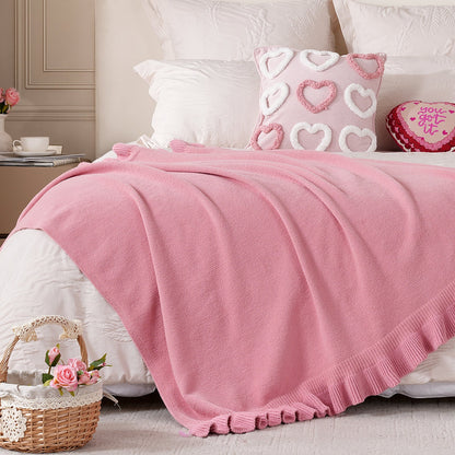 Ruffle Knit Chenille Throw Blanket in Pink styled on a bed with heart decor pillows, creating a soft and romantic bedroom atmosphere. #color_Pink