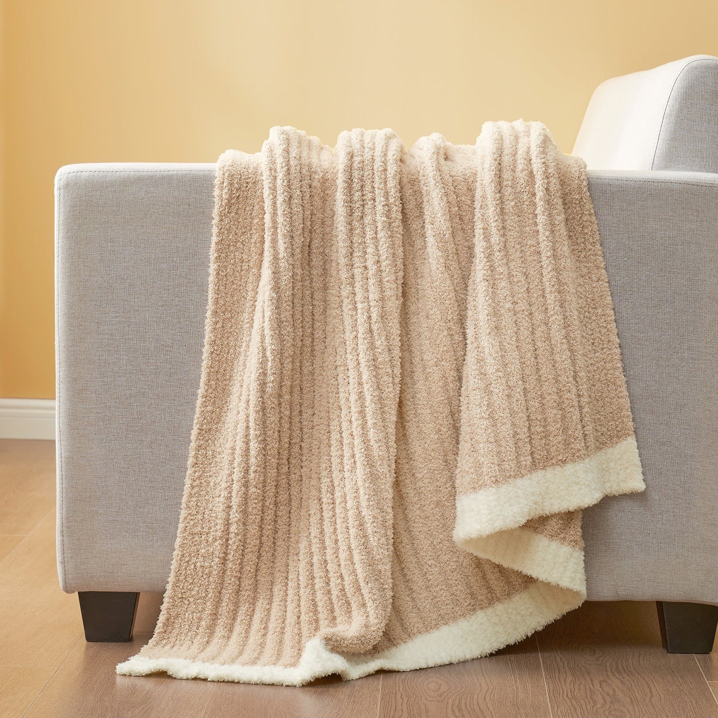 Soft Ribbed Feather Yarn Throw Blanket in Beige draped over the back of a sofa, highlighting soft ribbed texture and cozy fabric feel. #Color_Beige
