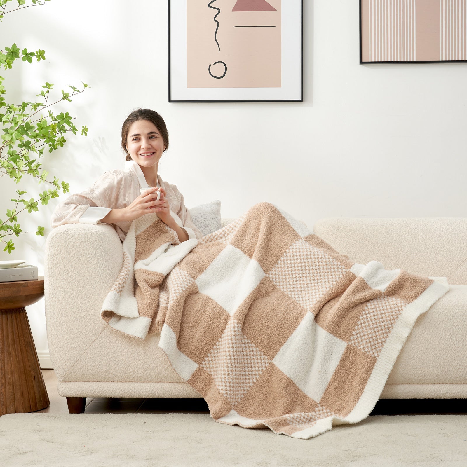 Woman relaxing on a sofa while using Checkered Feather Yarn Throw Blanket in Beige in a cozy room setting. #color_Beige