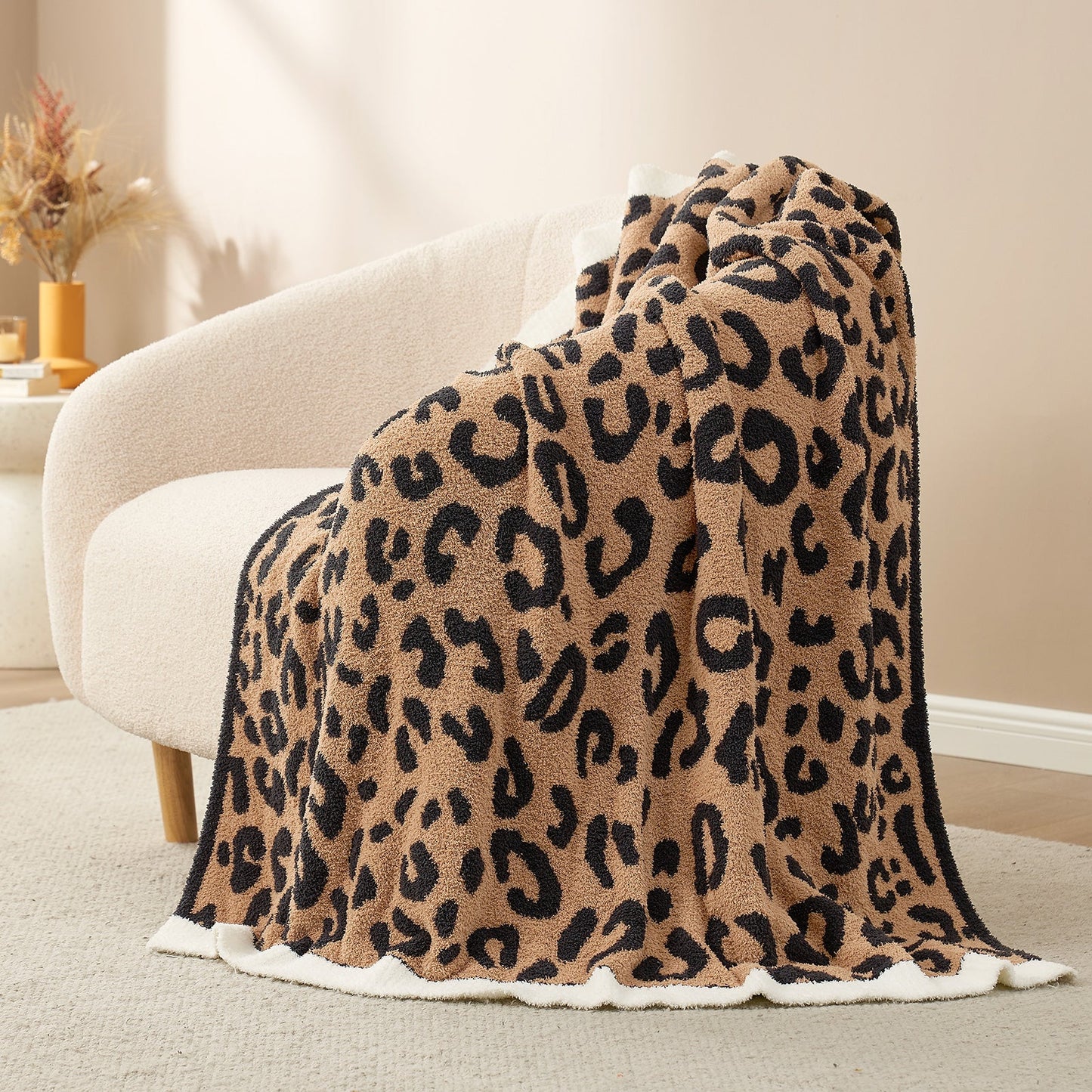 Reversible Leopard Feather Yarn Throw Blanket in Black draped over an armchair, showcasing its bold leopard pattern and soft texture. #color_Black