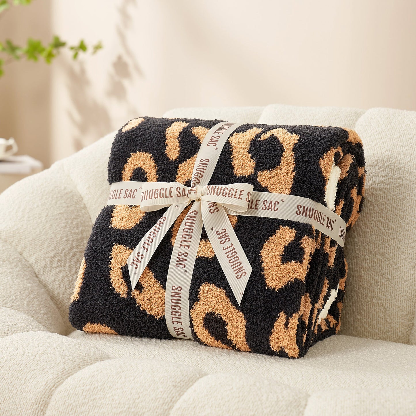 Reversible Leopard Feather Yarn Throw Blanket in Black neatly folded with ribbon, perfect as a cozy gift option. #color_Black